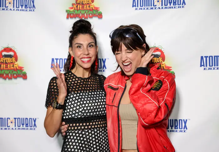 Two guests laughing mid-pose, one in a black mesh top, the other in a red bomber jacket.