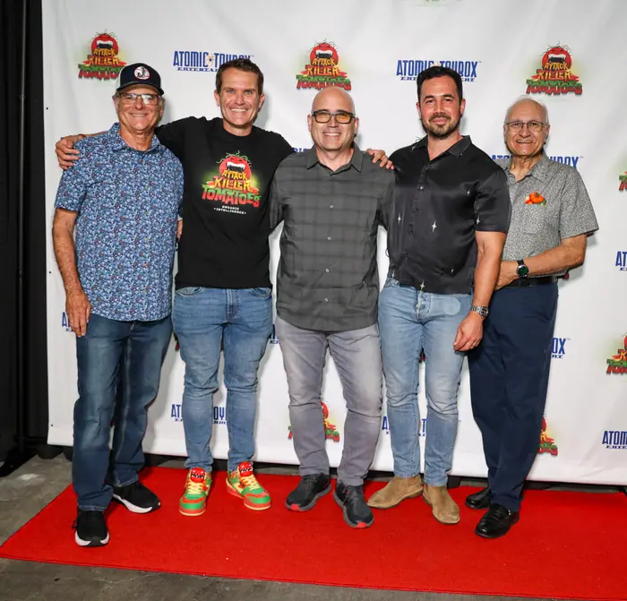 Five men standing shoulder to shoulder on the red carpet in front of the step-and-repeat.