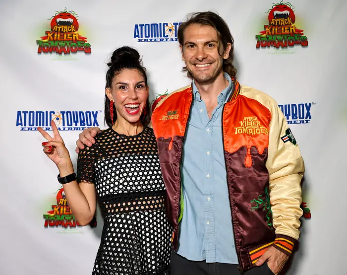 Two guests posing together, one flashing a peace sign, the other in a Killer Tomatoes varsity jacket.